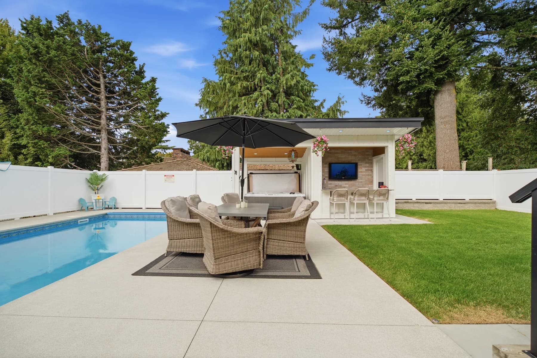 A contemporary home built around its back garden: pool and outdoor kitchen under a cedar soffit, a waterfall island, and a covered bar that works as a second living room.