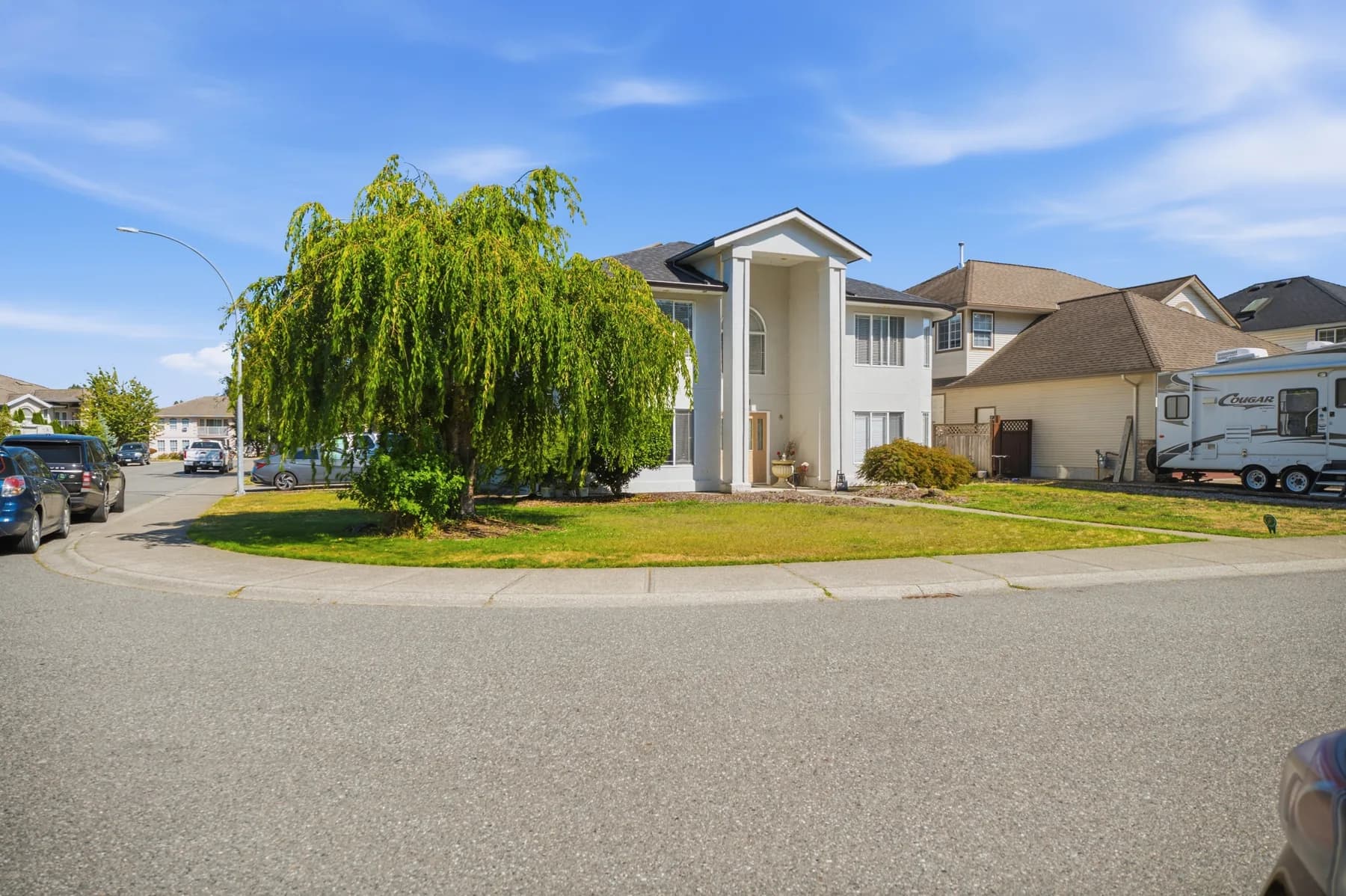 A two-storey family home: the street approach, a white island kitchen, the bay-window living room, a curved staircase and the full rear garden.