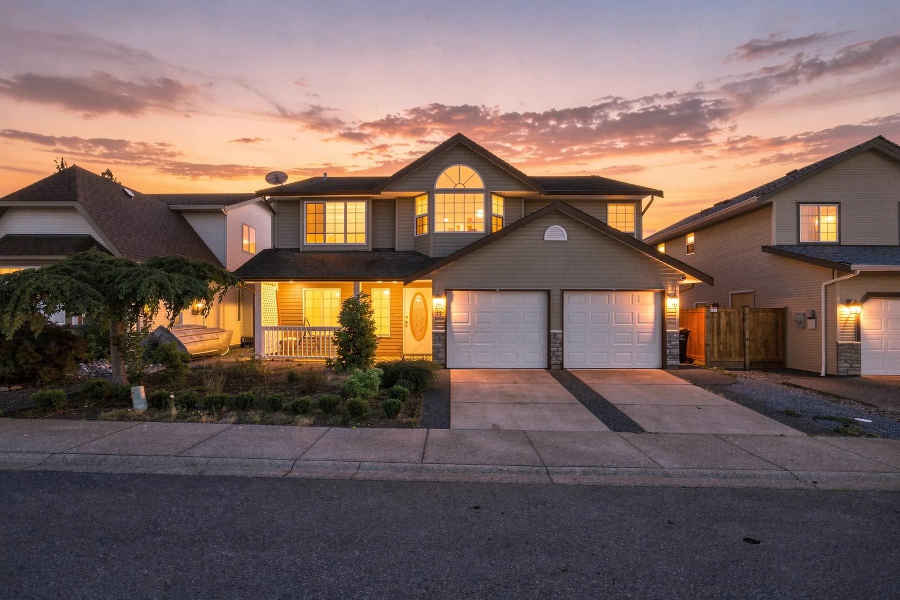 A twilight front elevation with every window lit, then the interior in daylight: kitchen, a bright lower living space, the covered deck and the full rear yard.